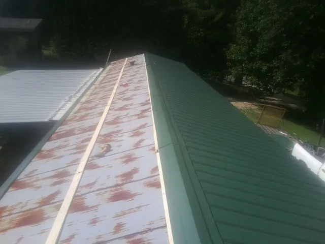 Old rusted panels beside newly installed green metal roofing — Wind Damage Roof Repair by Roofing Brothers in Stockdale
