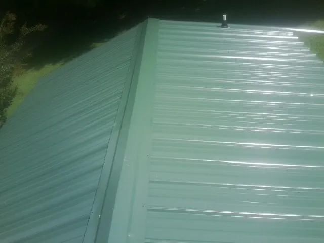 New green metal panels meeting at the ridge of a roof — Flat Roof Repair work by our crew in Stockdale