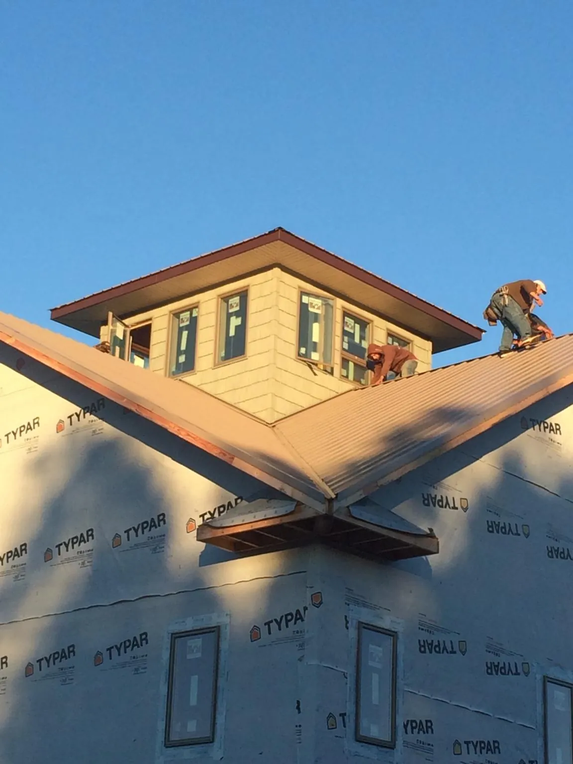 Roofers working around a rooftop cupola on a new metal roof at sunset — Roof Waterproofing in Stockdale by Roofing Brothers